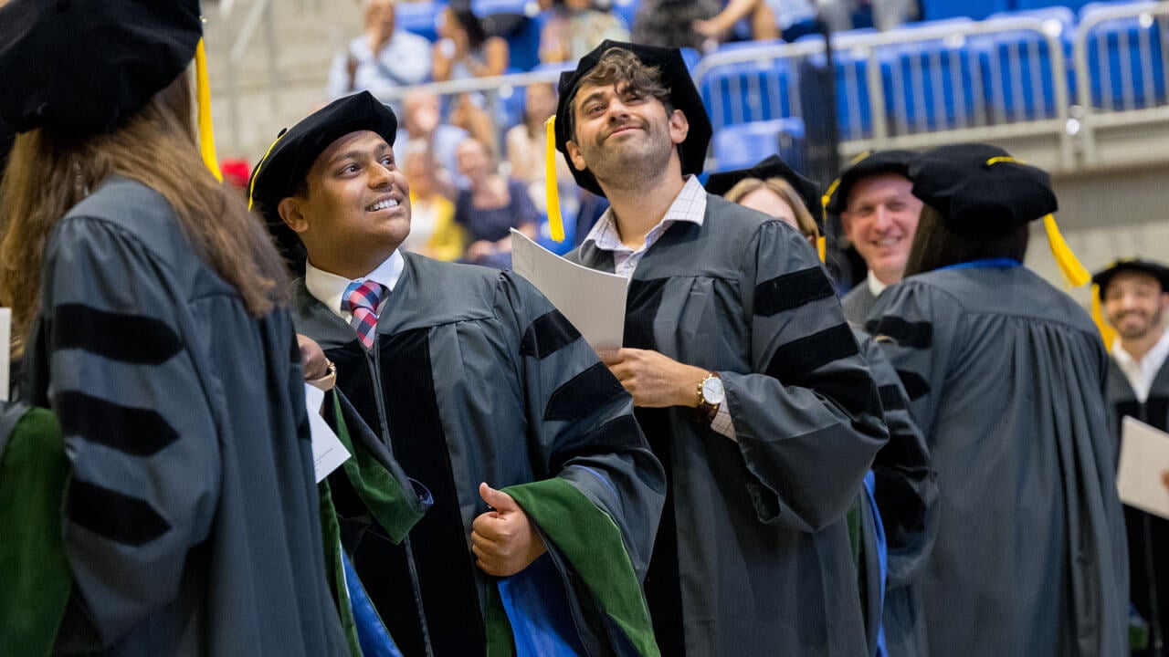Line of students smiling at the audience during medicine graduation