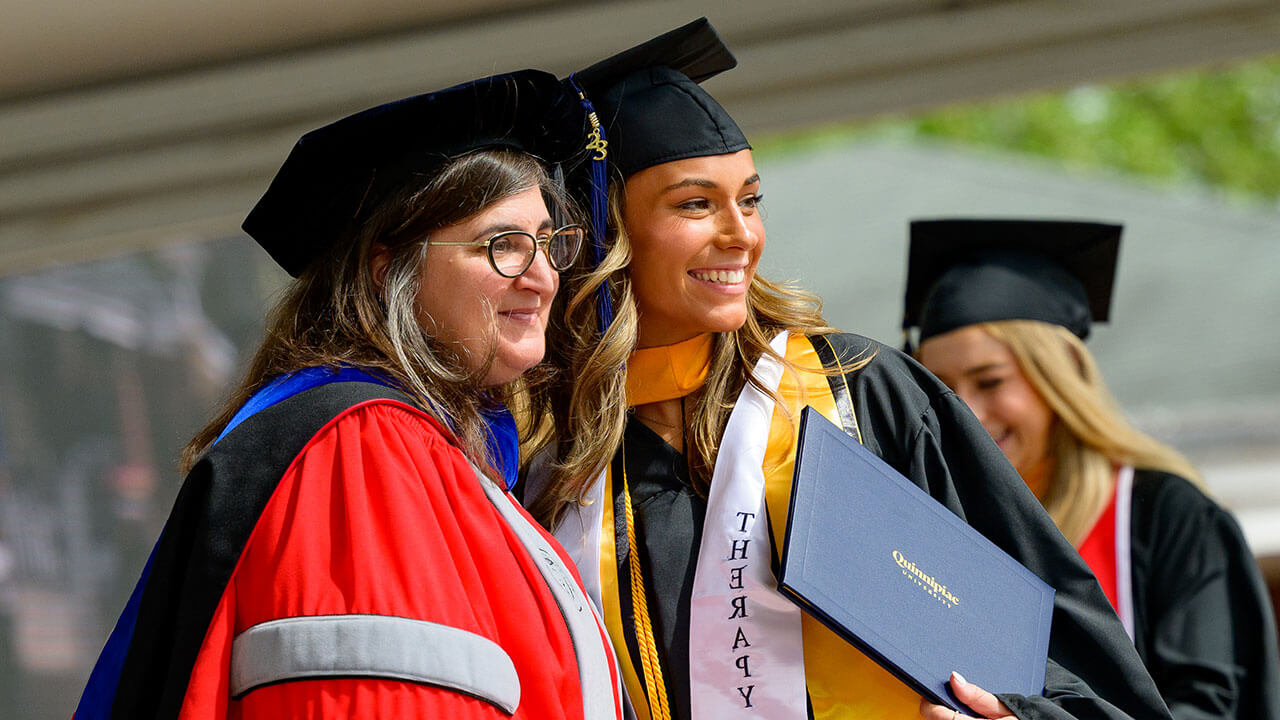 female graduate poses with the dean of health sciences smiling broadly