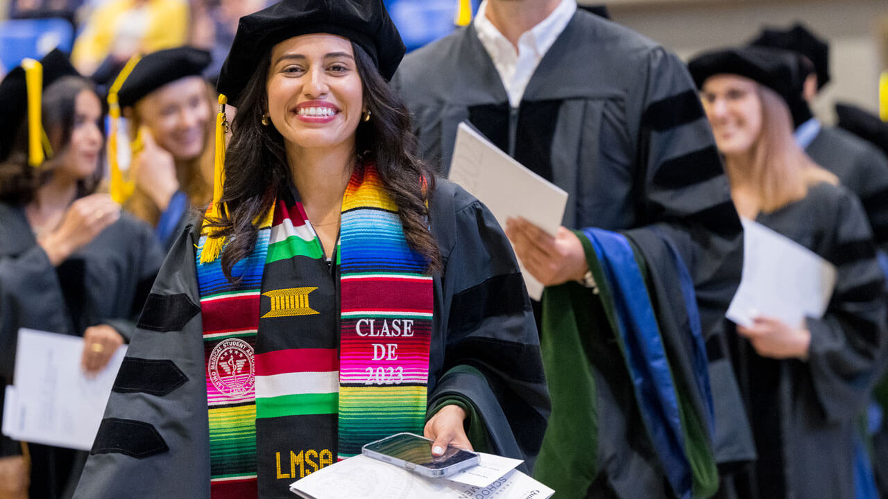 Student wearing rainbow sole and smiling for photo during medicine graduation