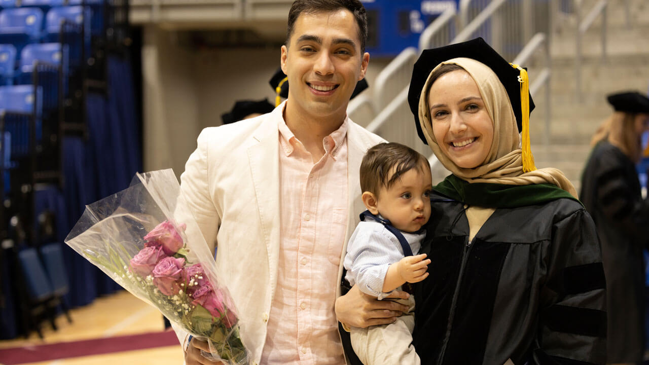Student posing with her husband and baby during Medicine graduation