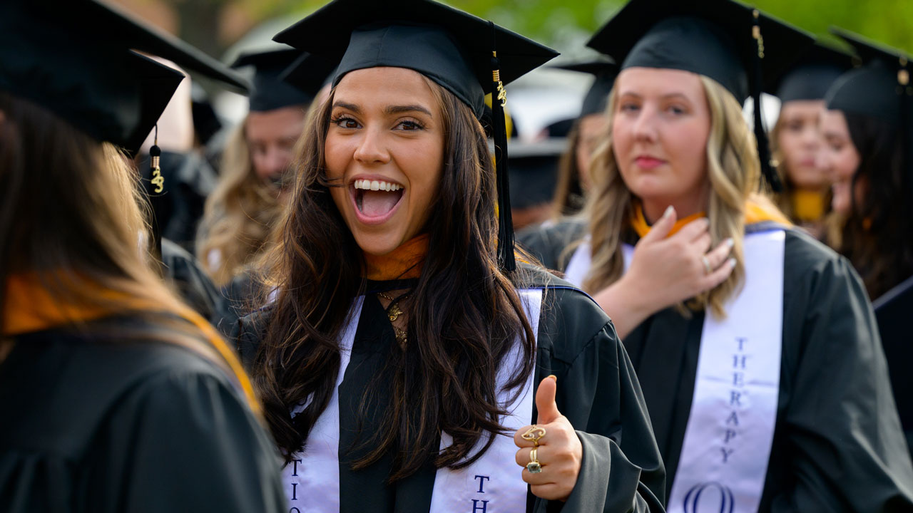 Graduate cheering in crowd of families after commencement