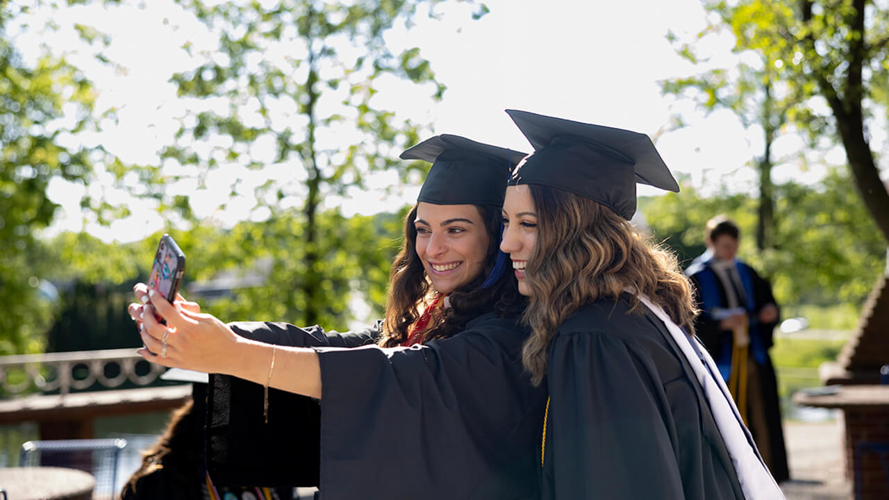Two graduates from the School of Communications pose for a selfie