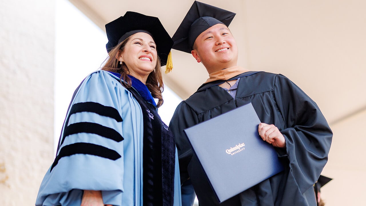 Graduate poses with diploma and Dean Holly Raider