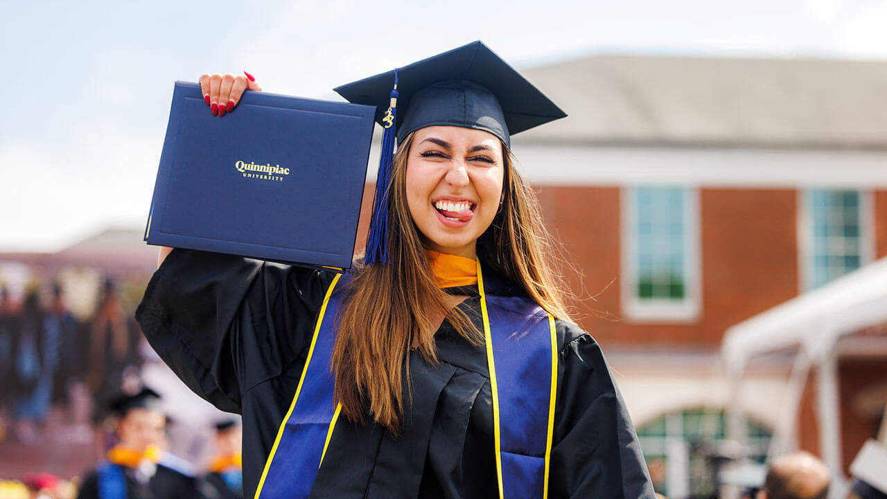Student sticks out her tongue with her diploma in hand