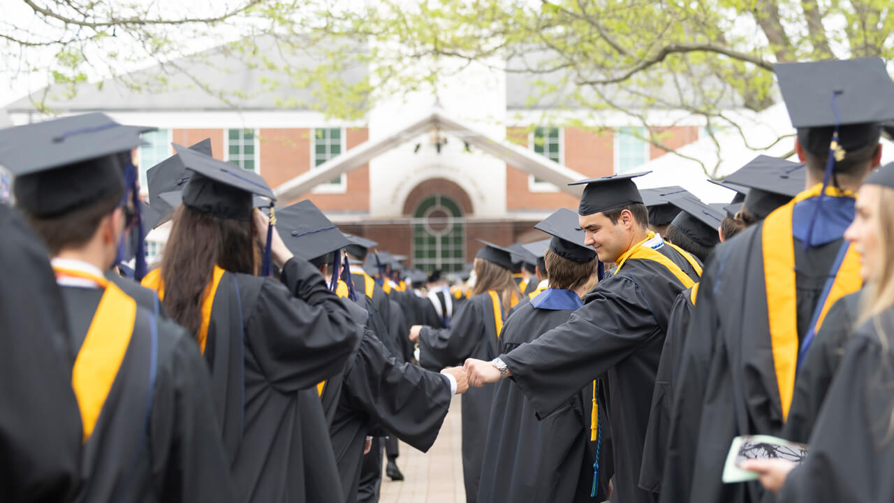 Graduates fist bump one another in line during Processional