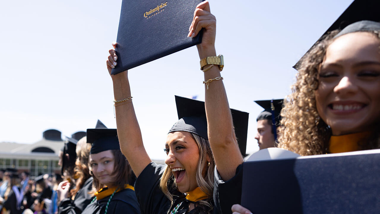 female graduate raises her diploma and cheers