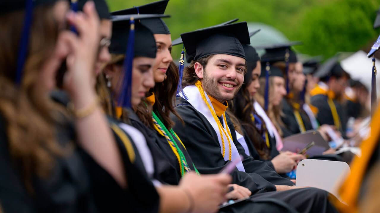 Graduate sitting in the crowd and smiling