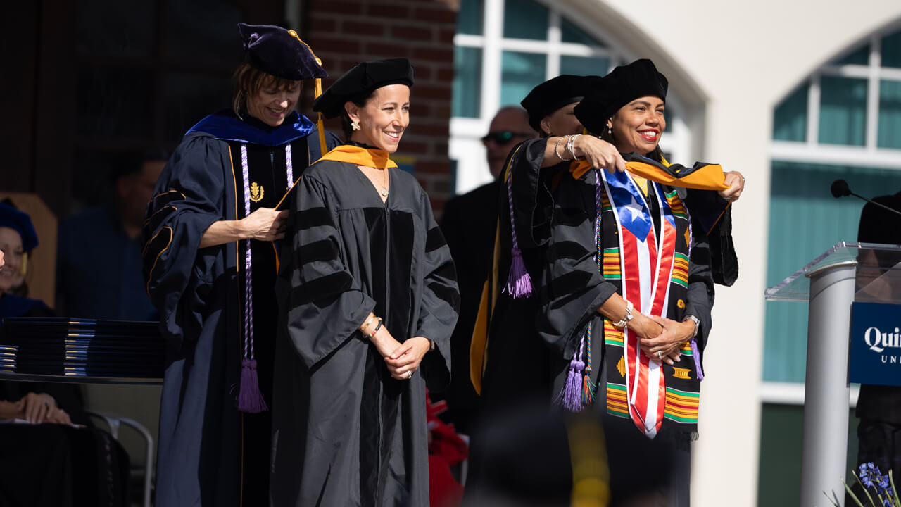 Two nursing graduates receive their doctoral hoods on the library steps