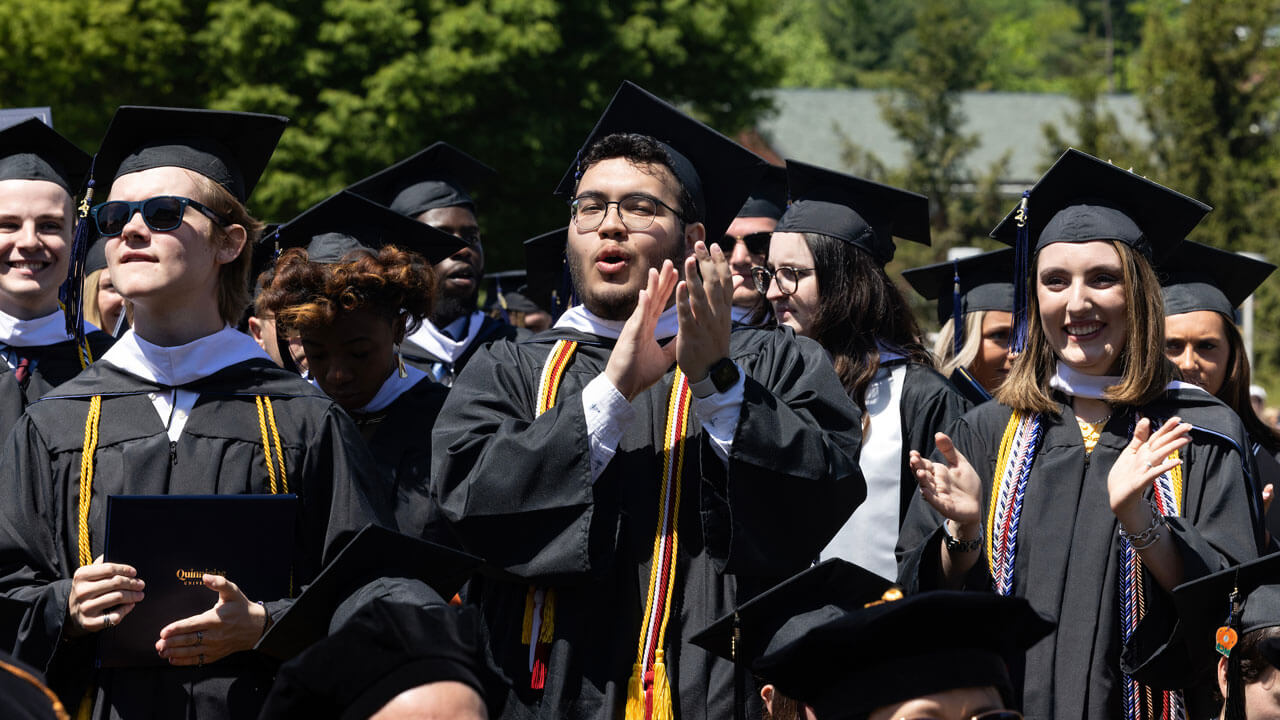 Graduates stand and clap after commencement ceremony for their success