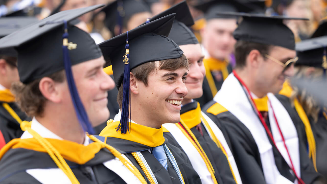 Graduates sit and smile during the Commencement speeches