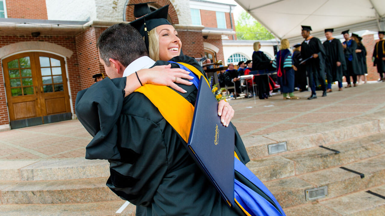 A graduate student hugs faculty member