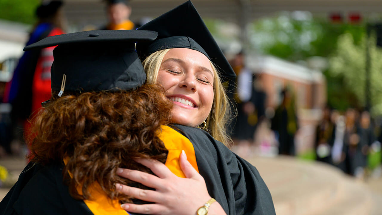 two female graduates hug each other right after coming off the stage