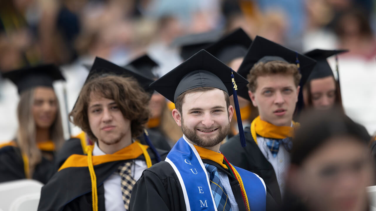 Graduate Charles Dunn smiles from his seat during Commencement