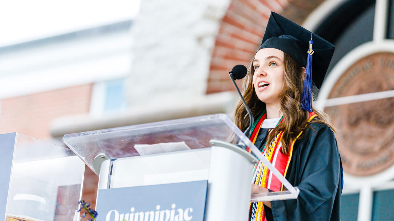 Kailee Heffler speaks into the microphone at the podium during Commencement