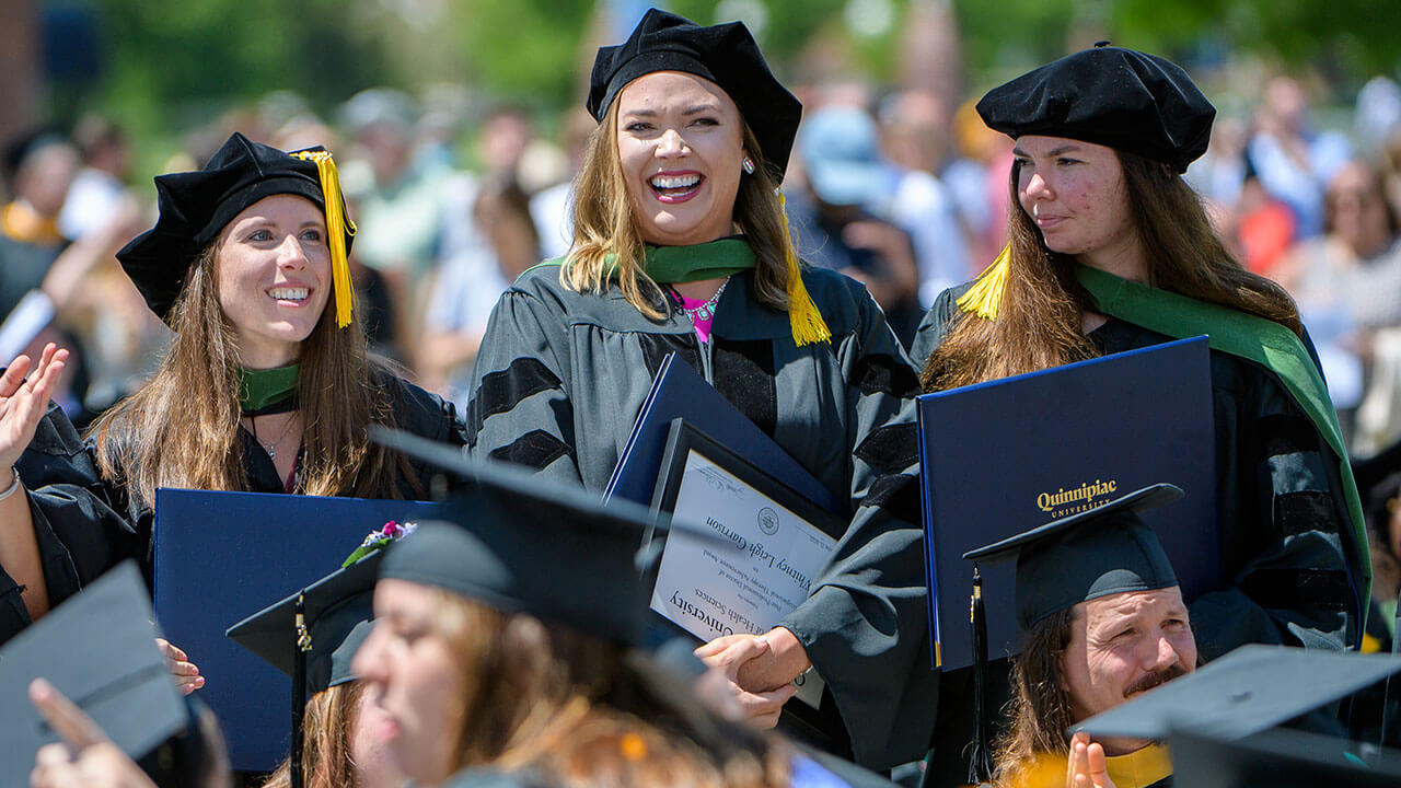 Graduates smiling and clapping during Commencement