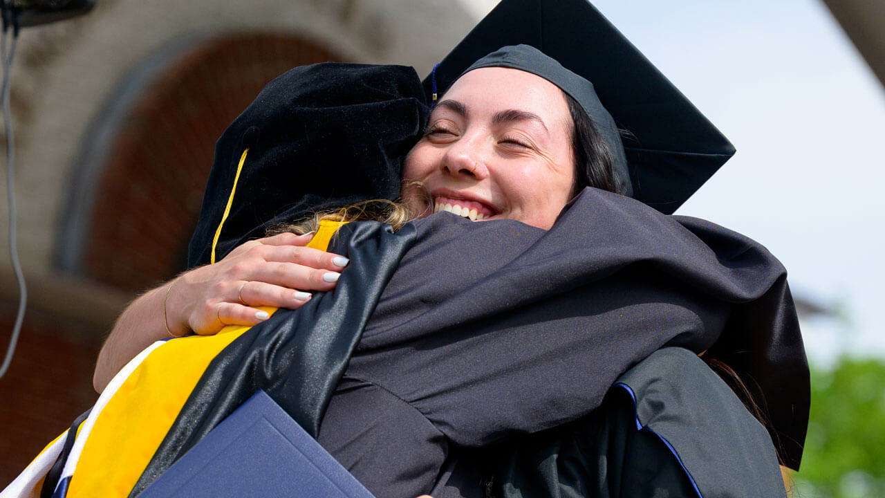 Two graduates hugging joyfully during commencement