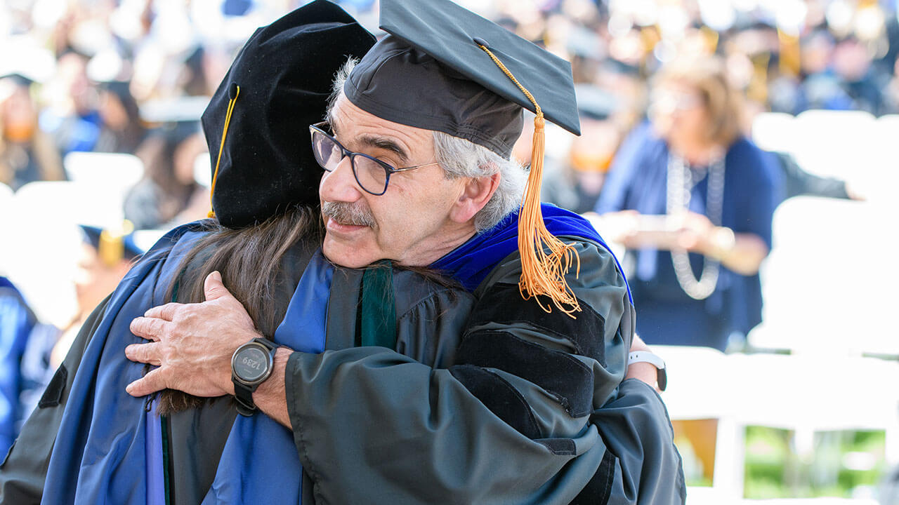 Faculty member hugs graduate student