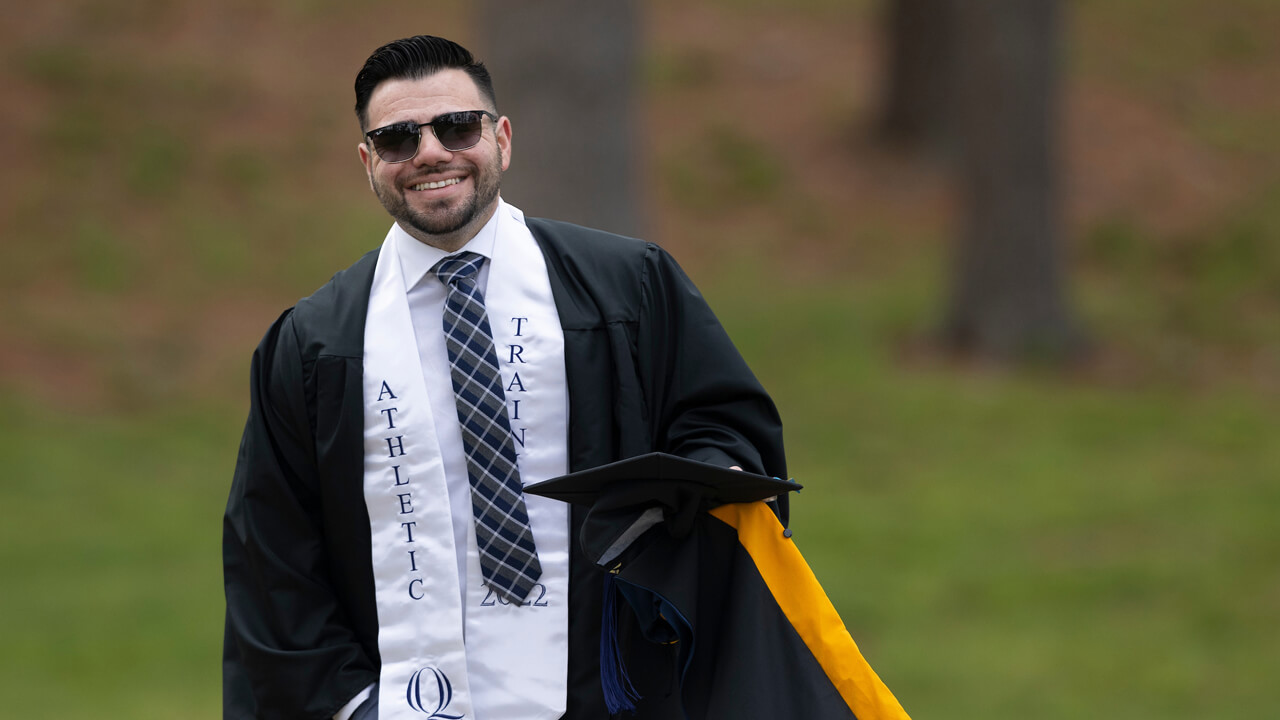 A student athlete smiles in his cap and gown