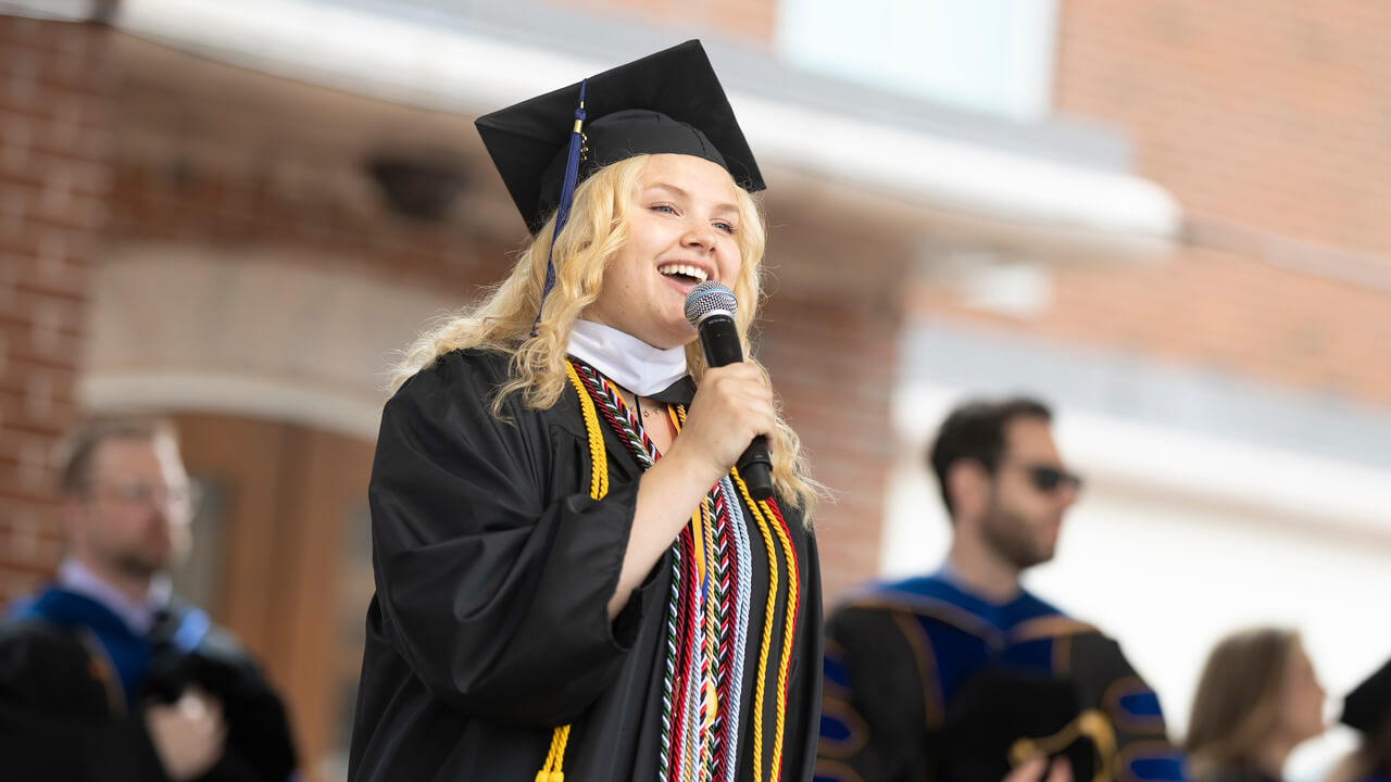 Sarah Cowden sings the national anthem from the stage during Commencement