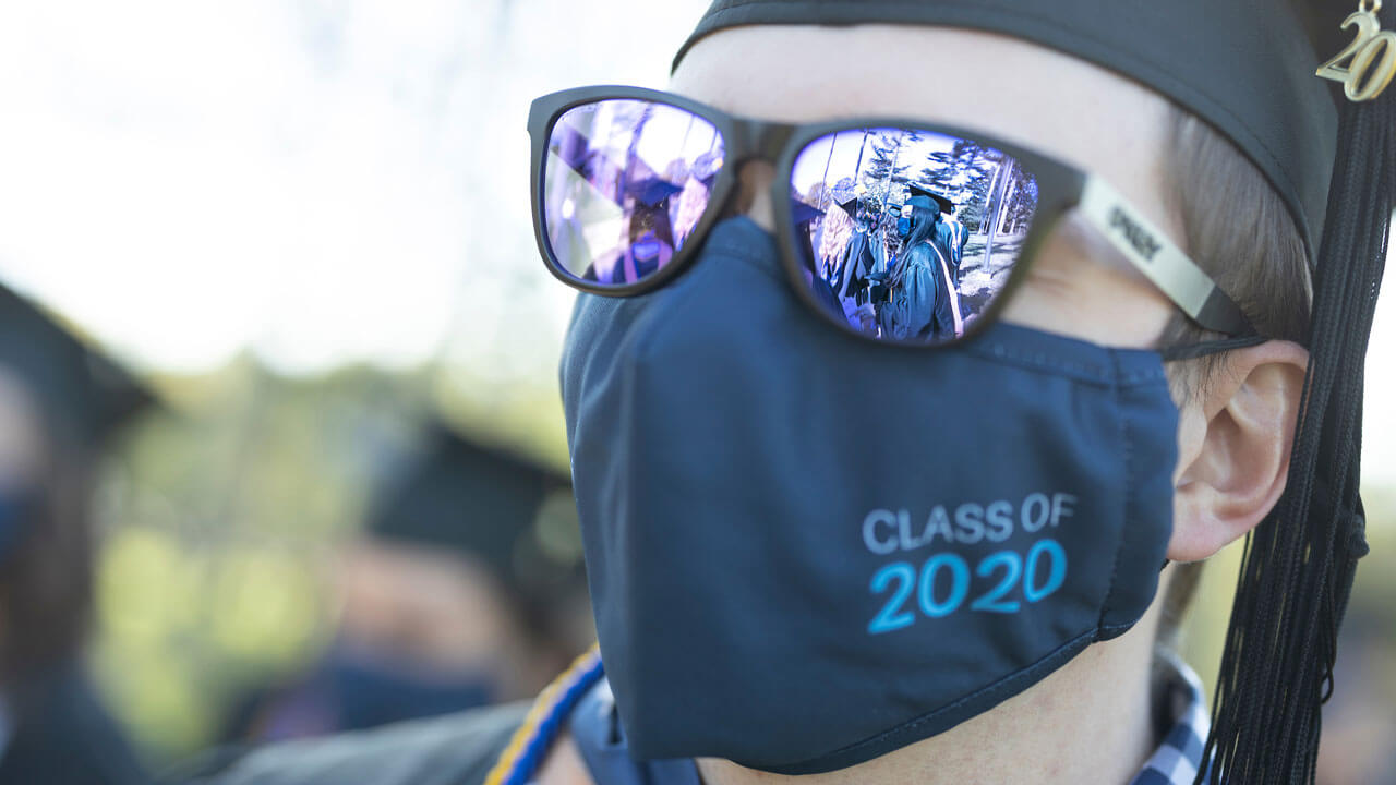 2020 graduate with sunglasses showing reflection of other graduates