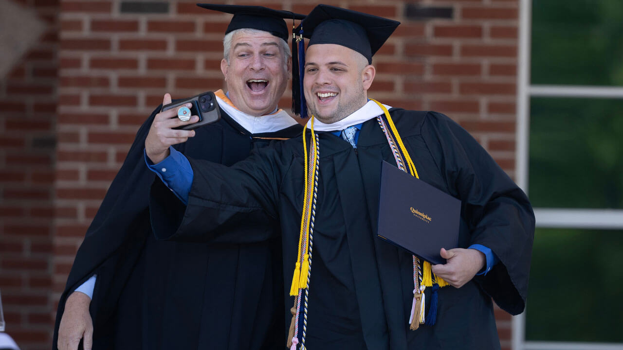 Dean Roush takes photo with a graduate