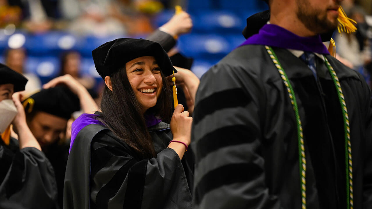 A graduate law student smiles as she moves her tassel