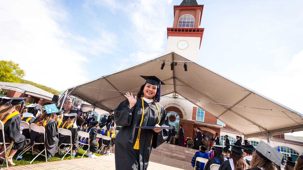 A graduate waves in front of the clocktower