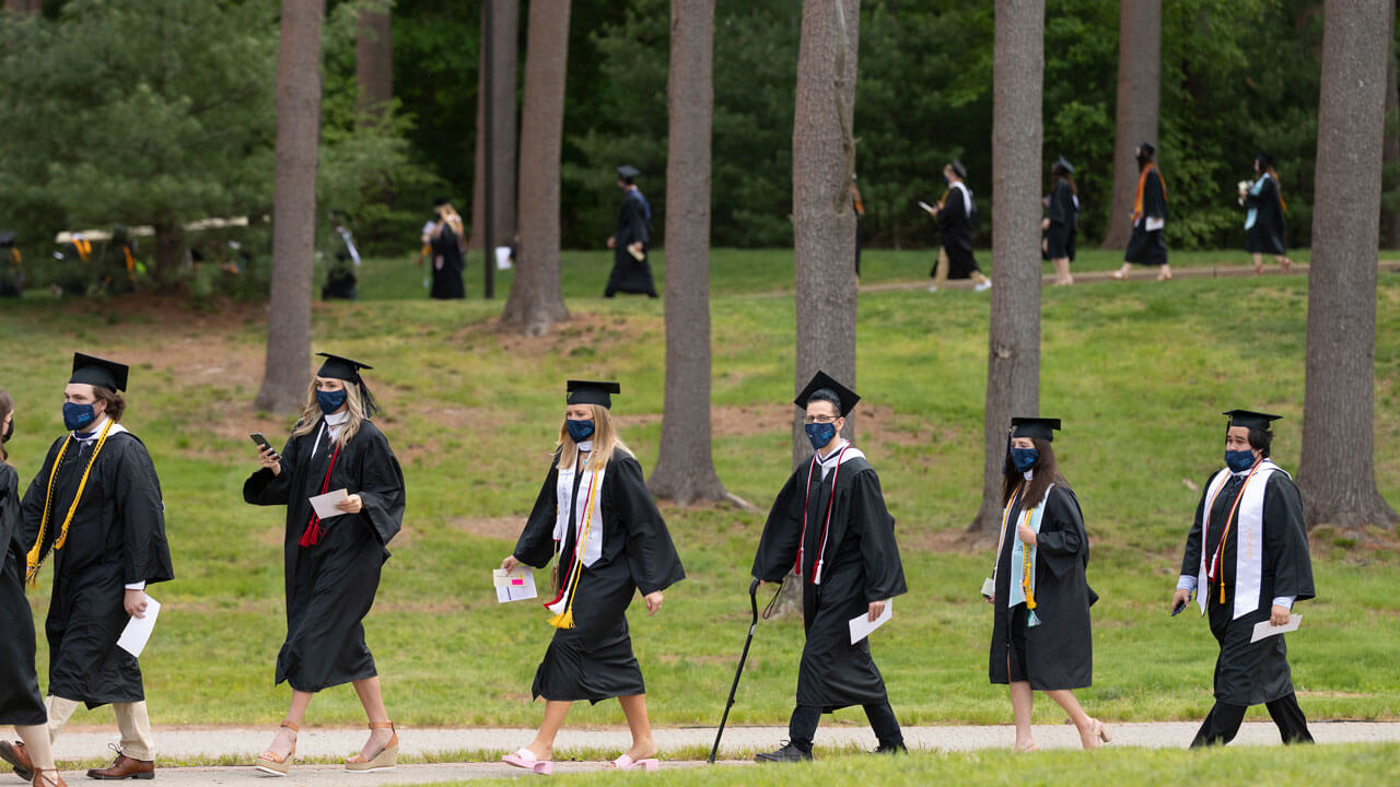 Graduates walking through the pine grove