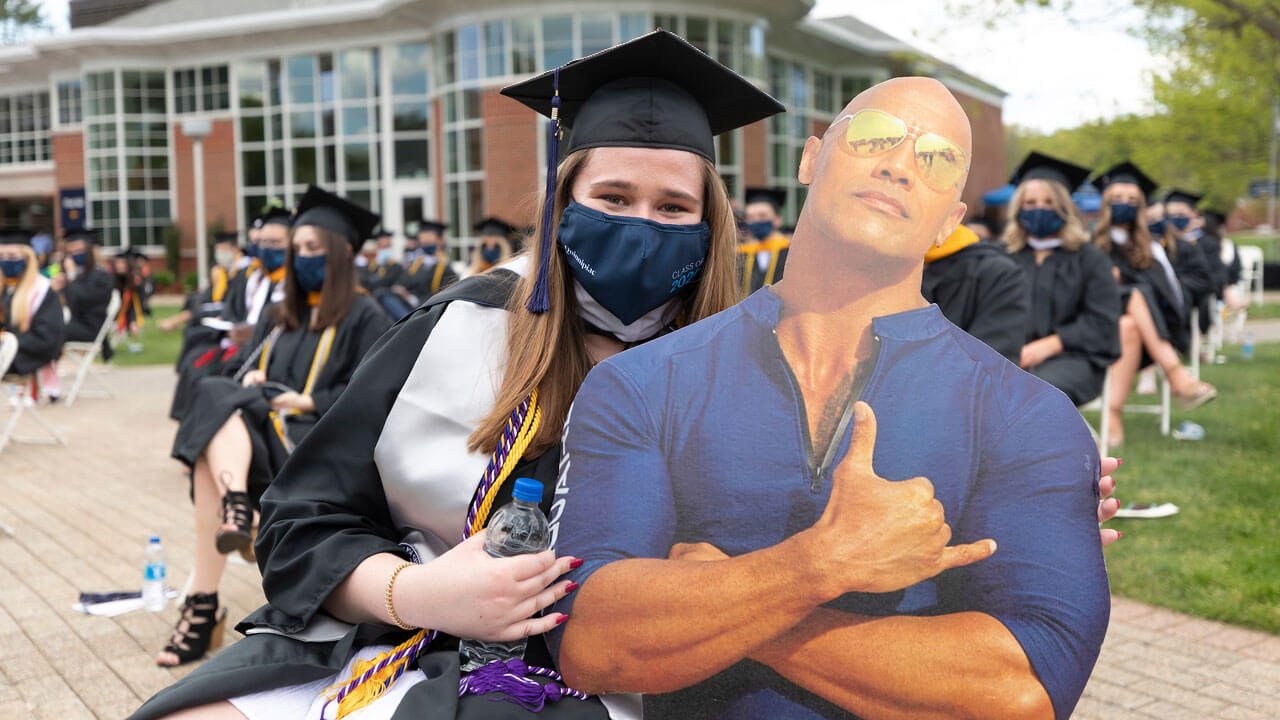 Graduate carrying life-size cutout of "The Rock"