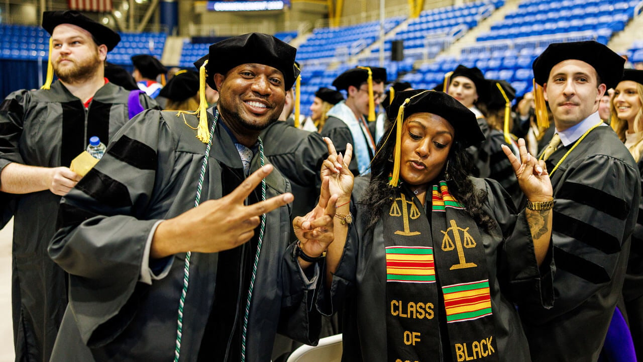 Two graduate law students throw peace signs while celebrating commencement