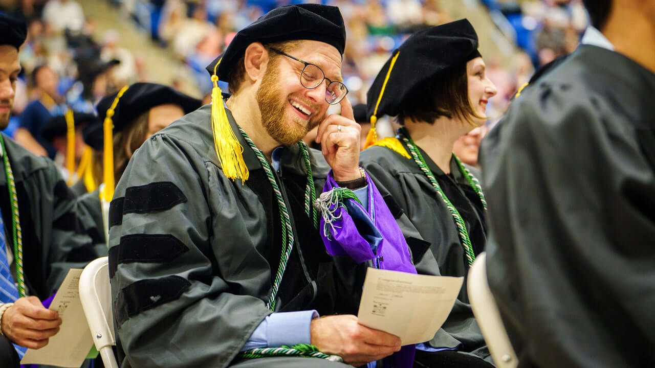 A graduating law student smiles while reading his professional oath