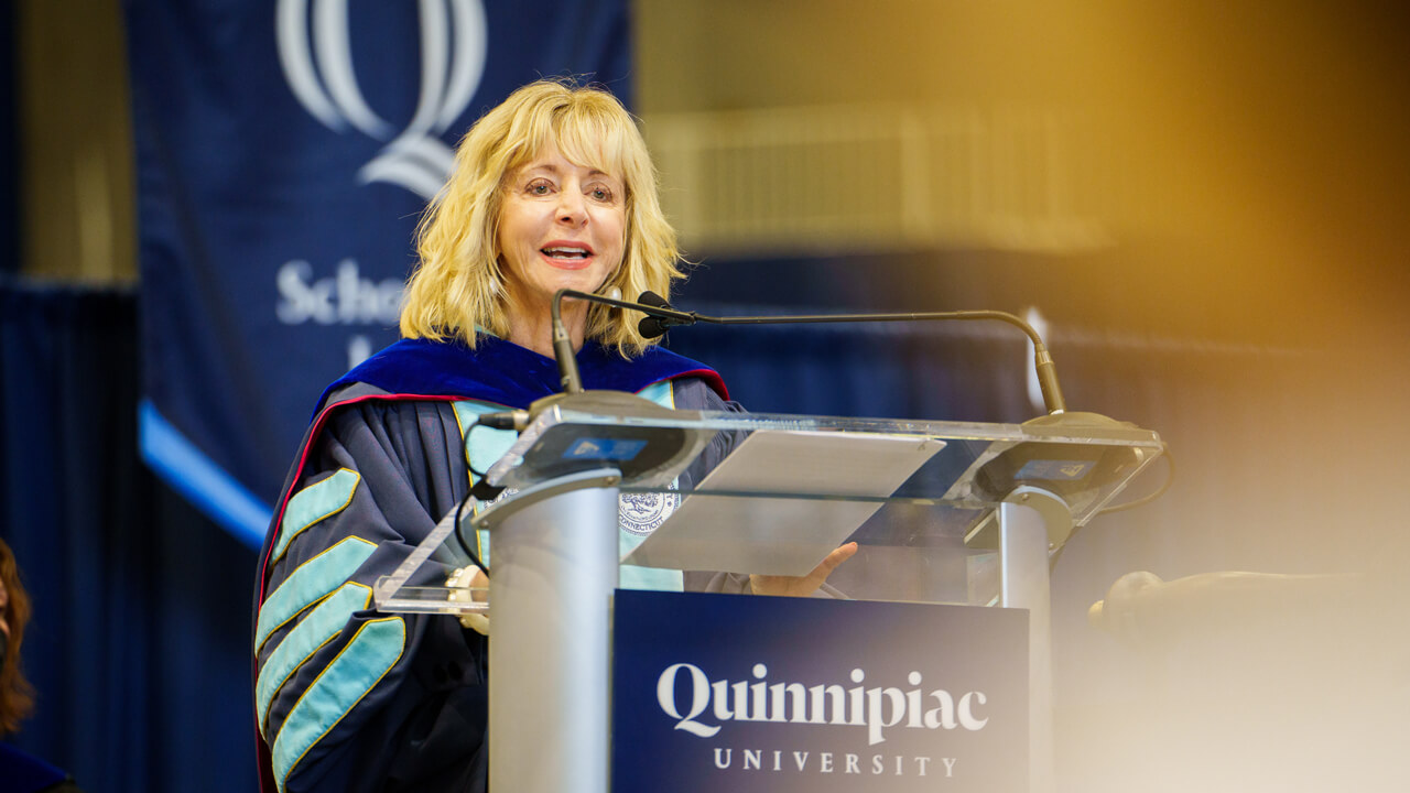 President Olian speaks from a podium that reads Quinnipiac during the law Commencement ceremony