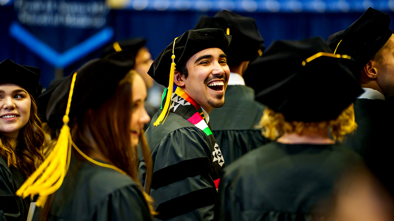 A graduate turns around in line and smiles