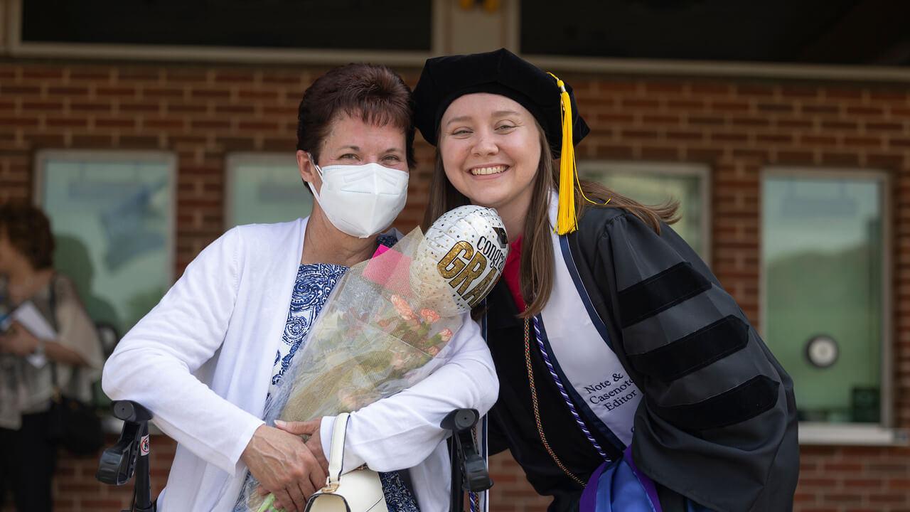 A graduate pauses for a photo with a family member
