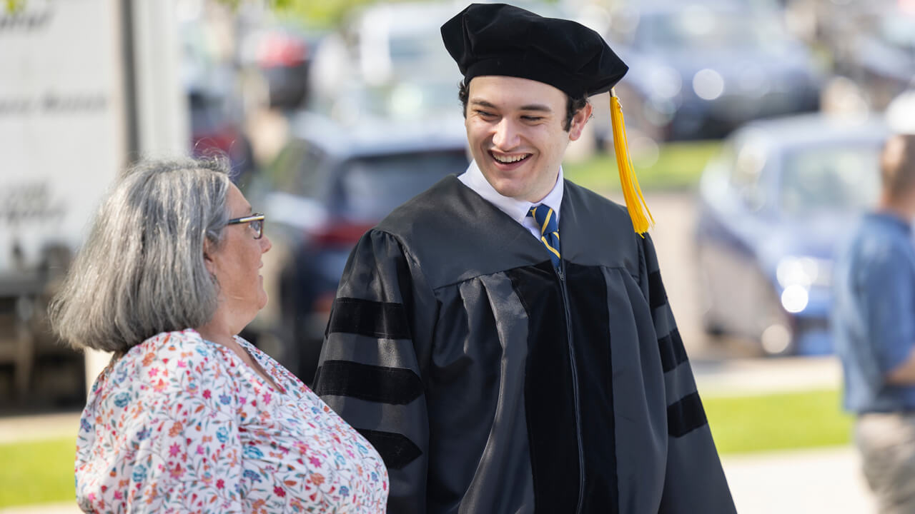 A graduate smiles as he walks with a family member