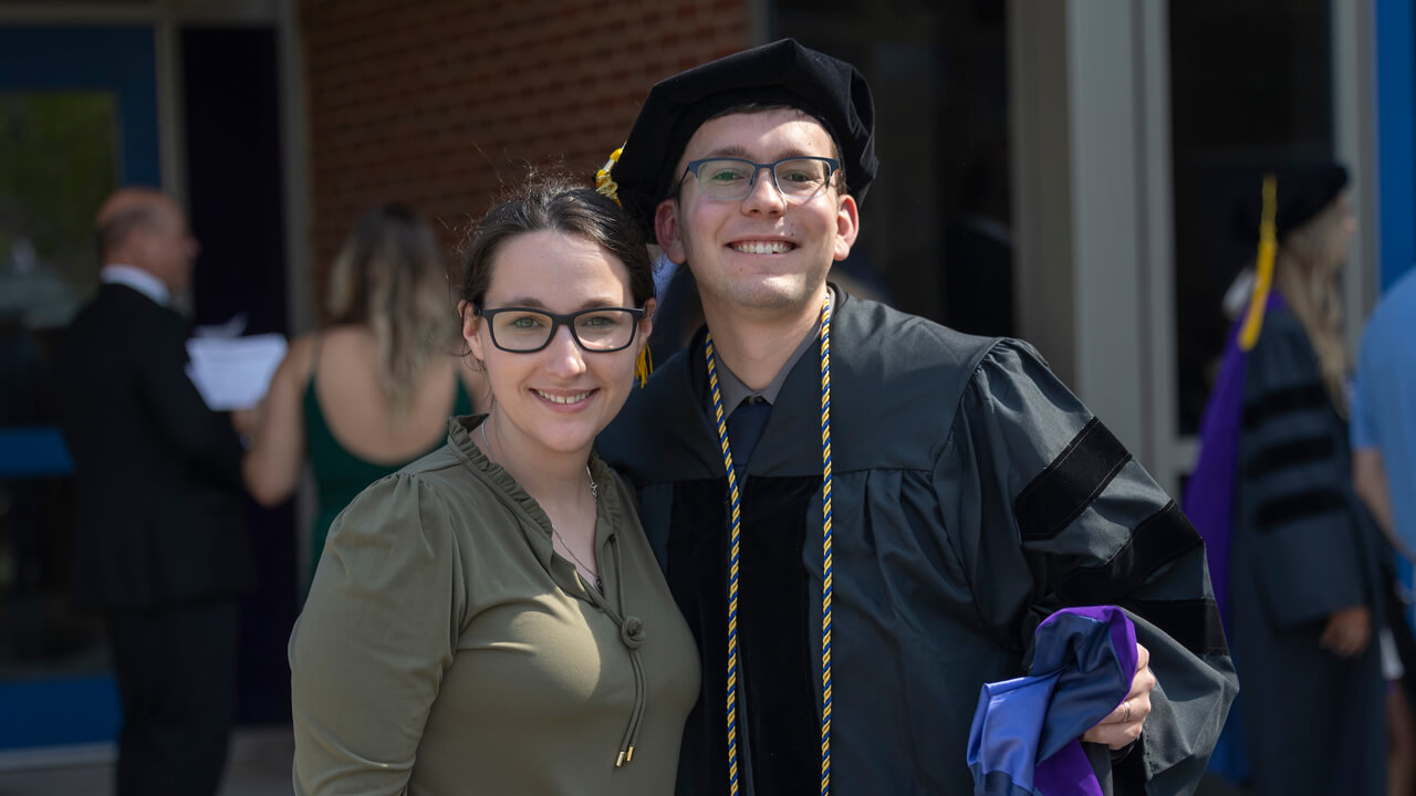 A graduate and a guest stand together for a photo