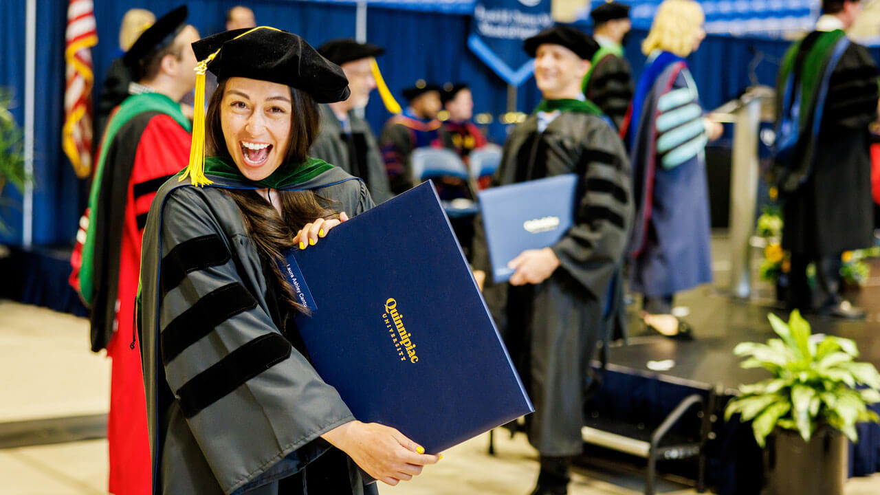 A medical graduate student smiles while holding her diploma