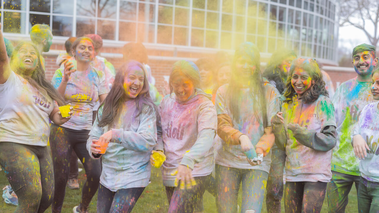 Students celebrating Holi, the Festival of Color with the tradition of throwing colored powder at one another.