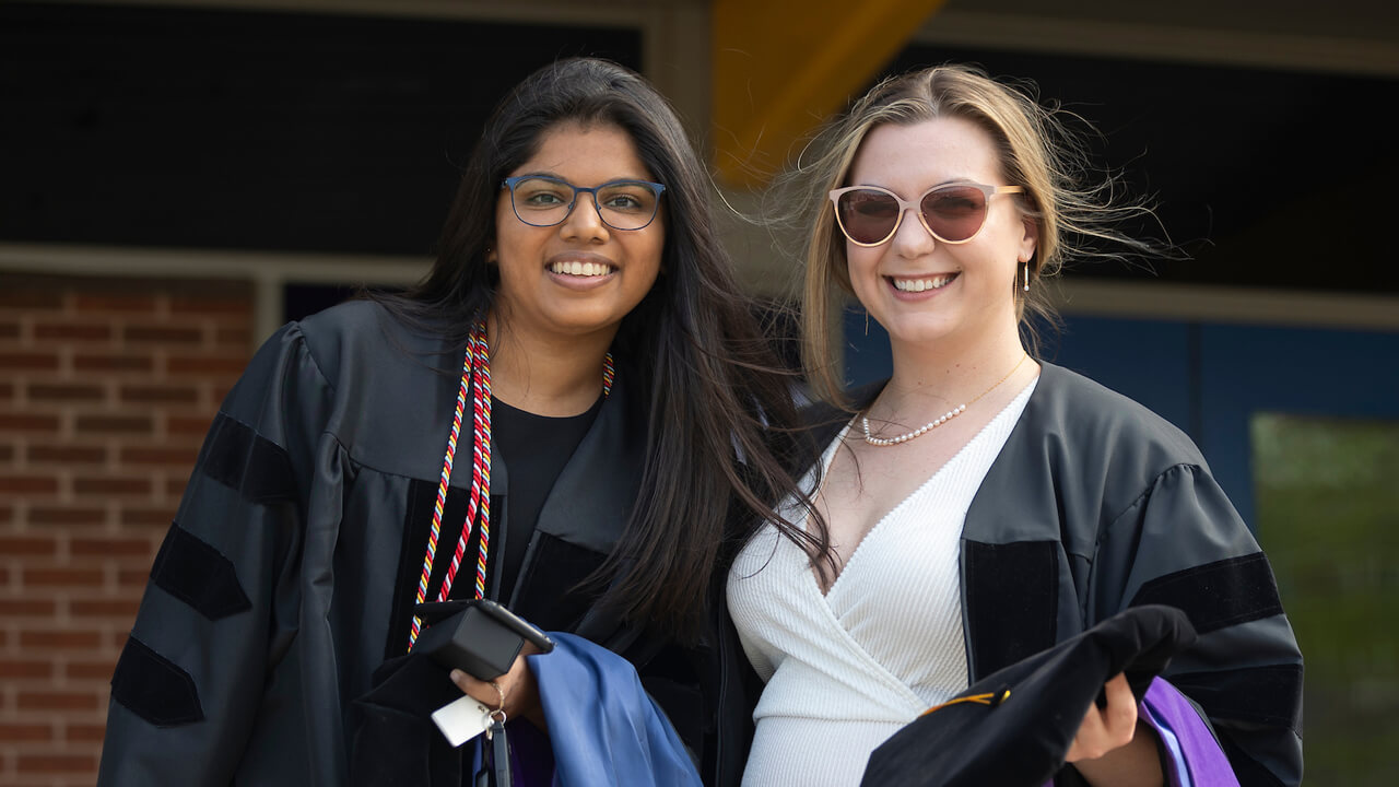 Two law graduates smile for a photo outside