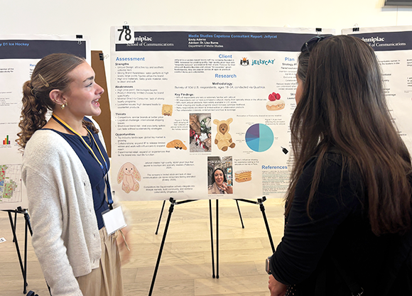 Student looking at poster and presenting to someone else looking at the poster