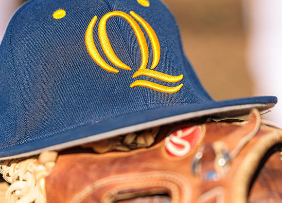 Baseball glove and a Quinnipiac hat on the baseball field