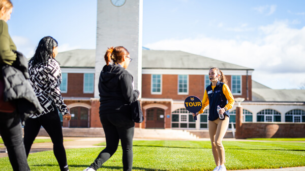A student tour guide leads a group across the quad during Open House