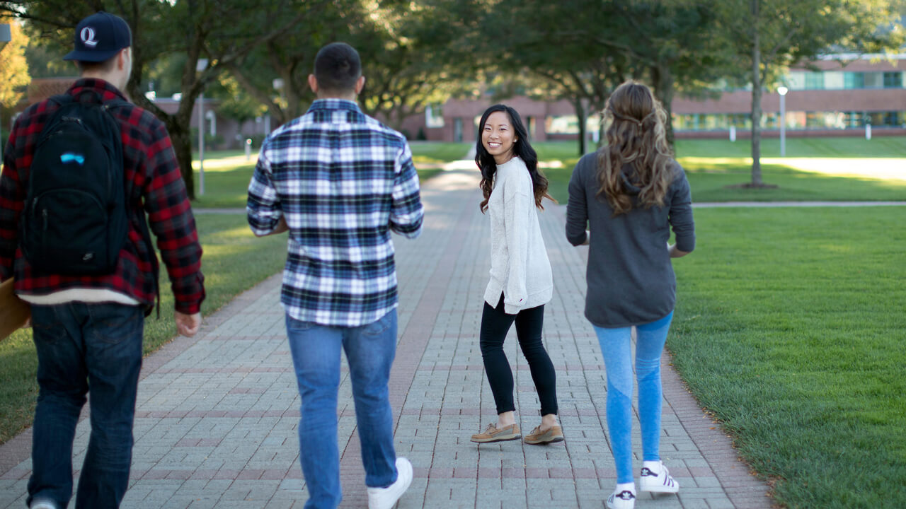 Four students walk across the Mount Carmel Campus quad