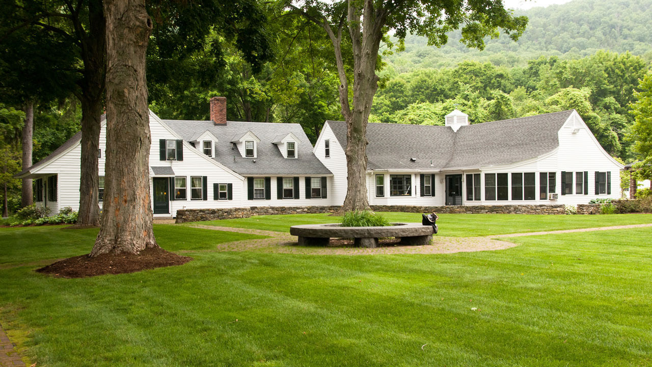 White colonial house with black trim and surrounded by nature