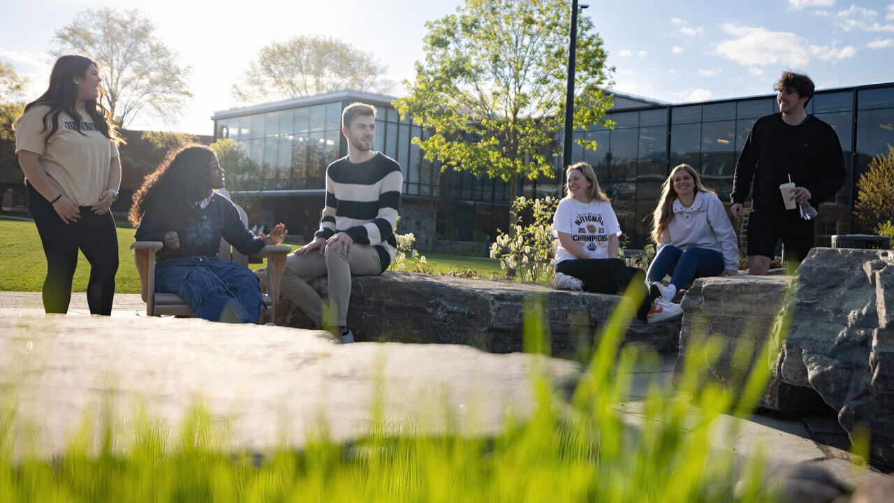Group of students sitting on a rock amphitheater, chatting