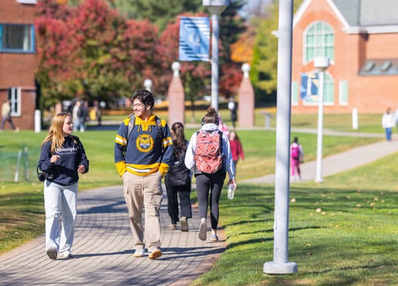 Students walk on a path across the Quinnipiac quad on a fall day