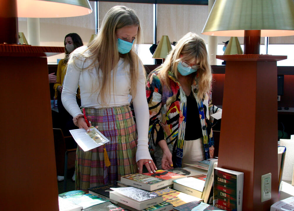 Two women browse among books.