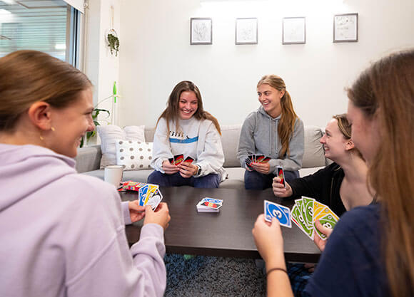 Students play a card game in their common area