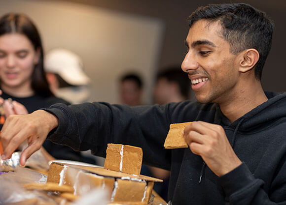 Student make gingerbread houses in their residence hall