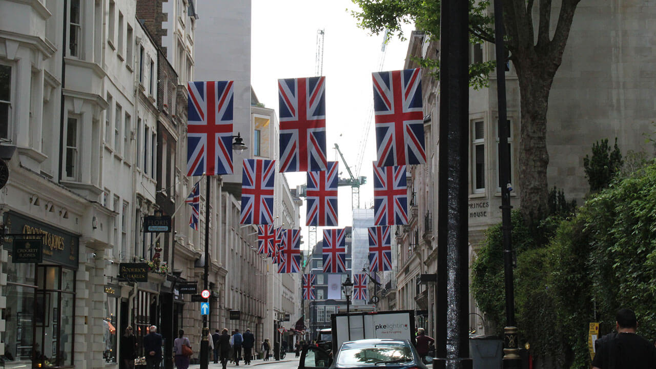 british flags hang between buildings over the street